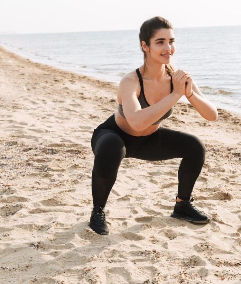 Vrolijke vrouw in sportkleding doet de Squat